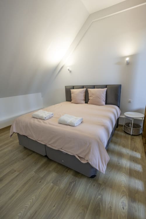 Chambre moderne à la Villa Chateaudine de l'hôtel Accolade, Châteaudun, avec lit gris, literie rose et parquet
