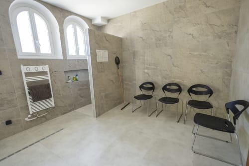 Salle de bains spa moderne à la villa Accolade avec murs en marbre, fenêtres cintrées, sèche-serviettes chauffant et chaises noires