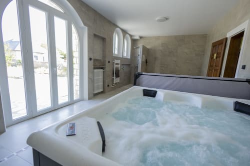 Villa de luxe avec jacuzzi, baignoire spa moderne et portes vitrées donnant sur le jardin à Accolade Châteaudun