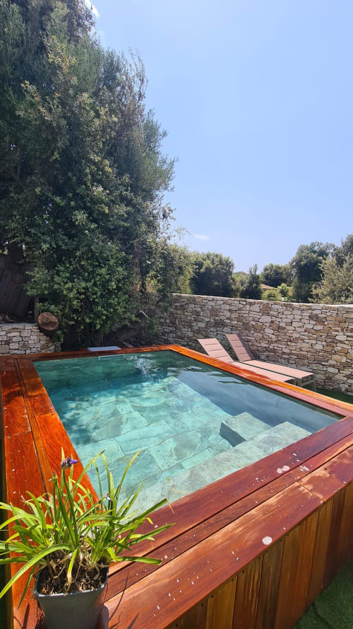 Piscine privée entourée de murs en pierre et d'arbres luxuriants à la suite de l'hôtel Perla Di Macchia à Bonifacio