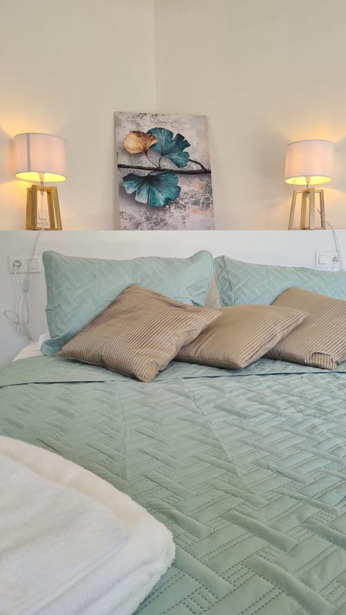 Suite chambre paisible à l'hôtel Perla Di Macchia à Bonifacio avec literie menthe, oreillers rayés, lampes doubles et décor botanique