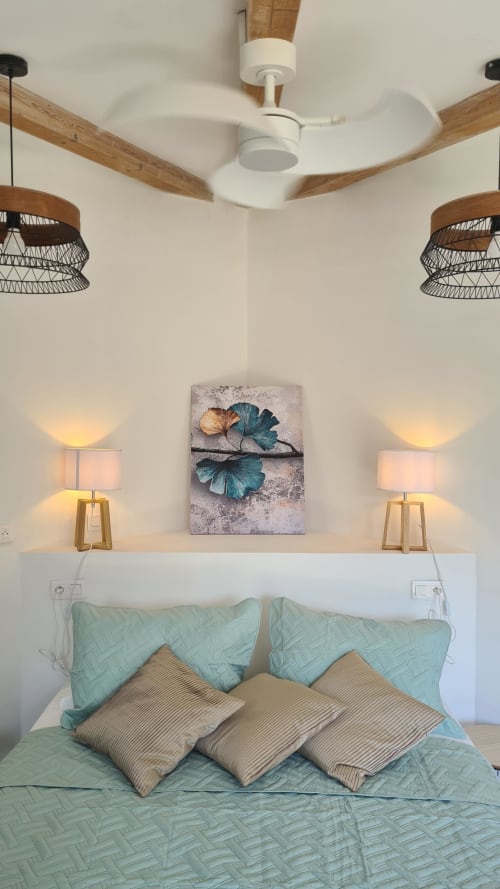 Chambre moderne à Perla Di Macchia à Bonifacio avec ventilateur de plafond, luminaires suspendus, linge de lit turquoise et décor botanique