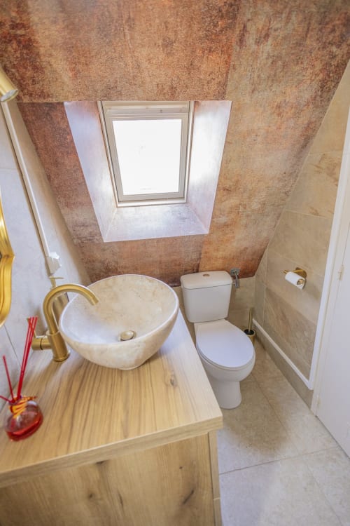 Salle de bain moderne de l'appartement L'école des sorciers à l'hôtel Accolade, Châteaudun avec lavabo en pierre rond, toilettes, lucarne et