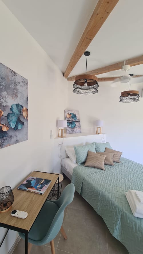 Suite chambre moderne à la Perla Di Macchia à Bonifacio avec poutres apparentes, linge de lit vert sauge et éclairage suspendu