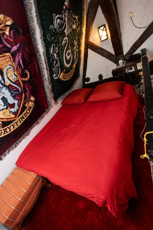 Chambre thématique Harry Potter à l'hôtel Accolade à Châteaudun avec literie rouge et bannières de maison