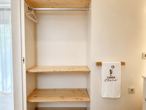 Guarda-roupa embutido com prateleiras em madeira e varão de penduração no Terra Clara Studios em Esposende, Portugal