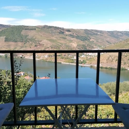 Mesa azul na varanda com vista para o vale do Douro em Folgosa, Portugal, com vinhedos em socalcos e colinas