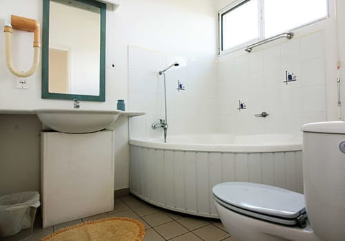 Salle de bain du grand bungalow à Balaga Vacances, Sainte-Anne avec baignoire, lavabo, toilettes et douche