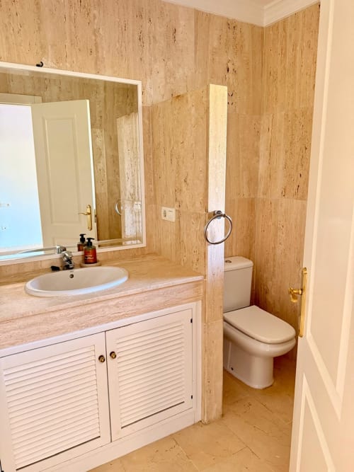 Baño moderno del hotel BH Marbella con paredes de azulejos de corcho, lavamanos y retrete