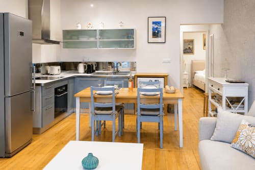 Modern apartment kitchen and dining area at Enjoy Nice hotel with wooden table, blue chairs, stainless appliances, and