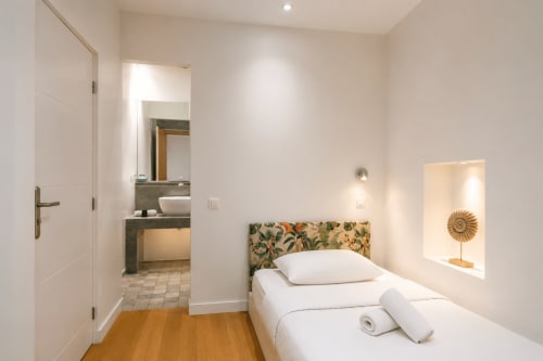 Modern bedroom at Enjoy Nice hotel in Nice with white bed, floral headboard, ensuite bathroom, and decorative sunflower
