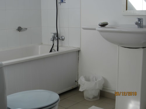 Salle de bain blanche et lumineuse avec baignoire, lavabo et toilettes au gîte Balaga Vacances à Sainte-Anne, Guadeloupe