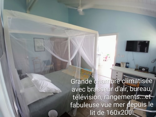 Spacieuse chambre climatisée avec lit à baldaquin, TV, bureau et vue sur mer aux Colibris Amoureux, Grand Bourg