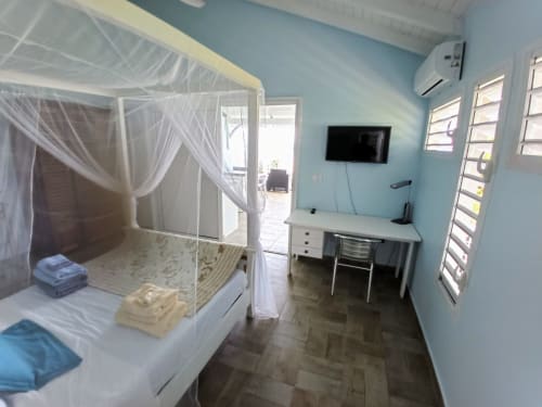 Chambre Loft Mer aux Colibris Amoureux à Grand Bourg : lit à baldaquin, bureau, TV et vue sur mer