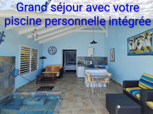 Appartement Loft Mer aux Colibris Amoureux avec piscine intégrée, murs bleus, kitchenette, coin repas et vue sur mer à Grand