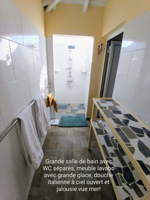 Salle de bain spacieuse avec WC séparé, grand miroir, douche italienne, murs jaunes aux Colibris Amoureux, Grand Bourg