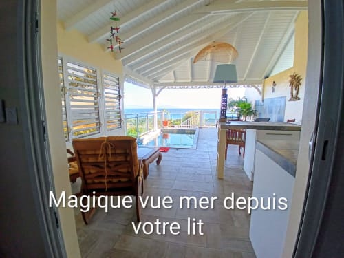 Chambre Loft Lagon aux Colibris Amoureux avec vue mer depuis le lit, cuisine et terrasse couverte à Grand Bourg