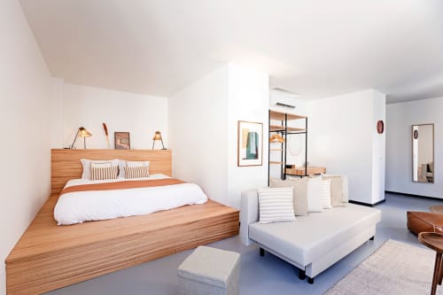 Modern studio apartment at Benefit Collection in Porto with wooden bed, white sofa, and garden view