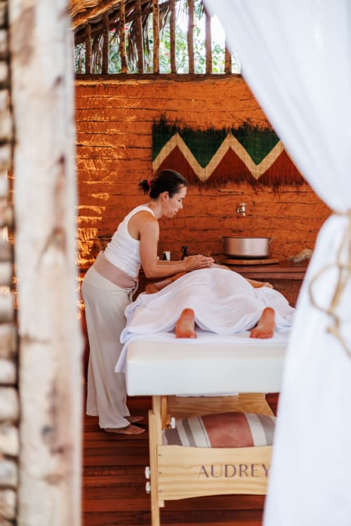 Terapeuta realizando massagem na La Cozinha Pousada em Cajueiro da Praia, spa rústico com detalhes em madeira