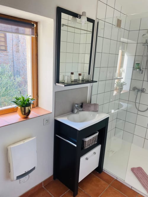 Cuarto de baño moderno en la casa rural La Vieille Demeure, Torreilles, con tocador negro, lavabo blanco, ducha alicatada y jardín