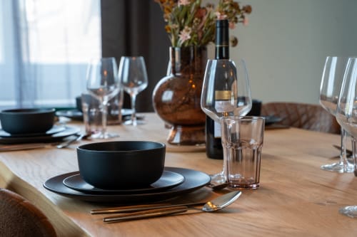 Élégante table dressée au 1 Péraudel avec couverts noirs, verres à vin et fleurs fraîches à Castres