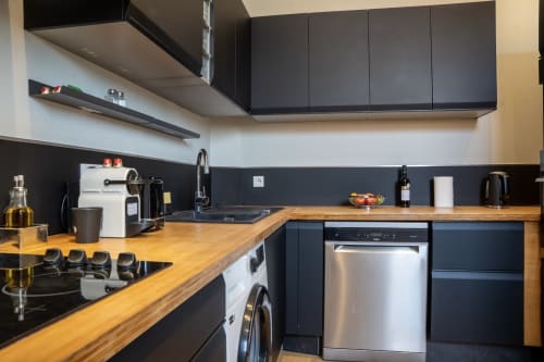 Cuisine moderne au Loft Prestige Le 1 Péraudel avec mobilier noir, plan de travail en bois et électroménagers inox
