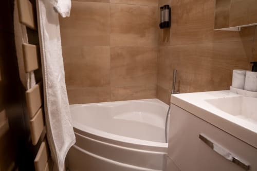 Salle de bain moderne du Loft Prestige à Le 1 Péraudel Suite & Appts, Castres, avec baignoire blanche et murs en carrelage beige