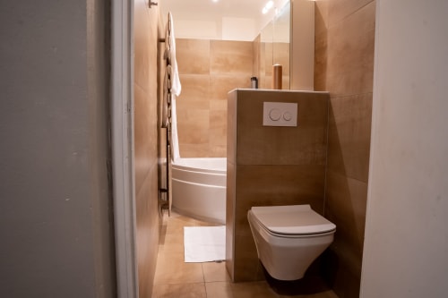 Salle de bain moderne du Loft Prestige à l'hôtel Le 1 Péraudel à Castres avec toilettes murales, carrelage beige et design contemporain