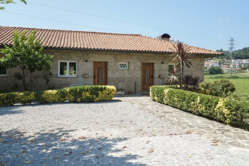 Casa da Vinha na Quinta de Carvalhal em Guimarães - cottage de pedra com telhado, sebes bem cuidadas, entrada em cascalho e jardim