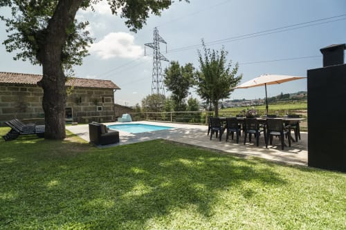 Vista do jardim da Quinta de Carvalhal com piscina privada, área de refeições sob guarda-sol e gramado em Guimarães