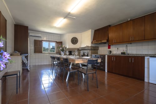 Espaçosa cozinha e área de refeições na Quinta de Carvalhal, Guimarães com móveis em madeira, mesa de jantar e vista para o jardim