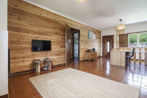 Espaçoso interior em madeira na Quinta de Carvalhal em Guimarães com sala de estar, TV, cozinha e vistas para o jardim