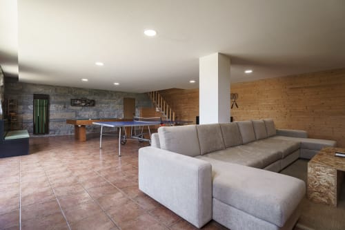 Sala de estar moderna com sofá cinzento em L, mesa de ping pong e escadas de madeira na Quinta de Carvalhal em Guimarães