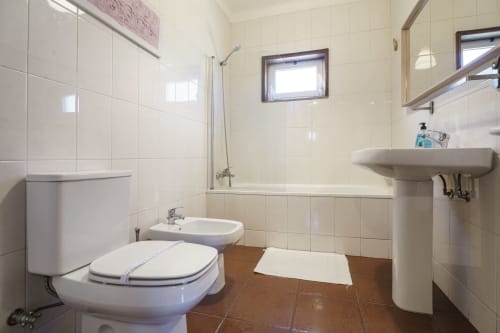 Banheiro limpo na Quinta de Carvalhal em Guimarães com vaso sanitário, bidê, pia, e chuveiro/banheira revestido em azulejos
