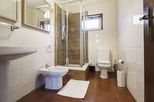 Banheiro moderno da Quinta de Carvalhal Casa da Vinha em Guimarães com box de chuveiro, vaso sanitário, bidê e espelho da pia