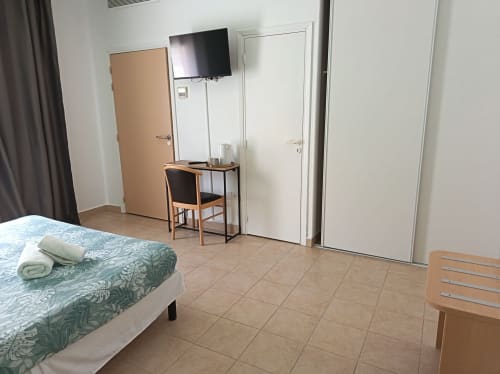 Chambre accessible du Clos du Thoronet avec lit, téléviseur, bureau et mobilier en bois sur carrelage