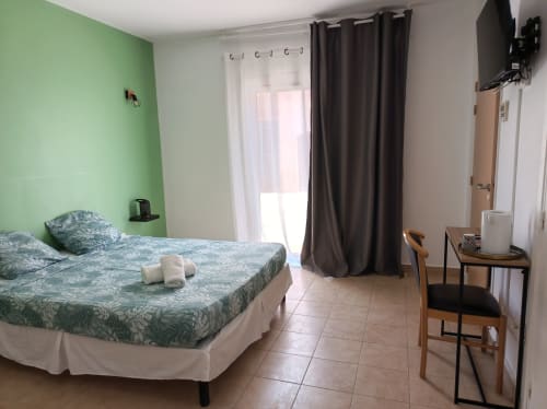Chambre double accessible au Clos du Thoronet avec mur accent vert, lit double et accès à la terrasse au Thoronet, France