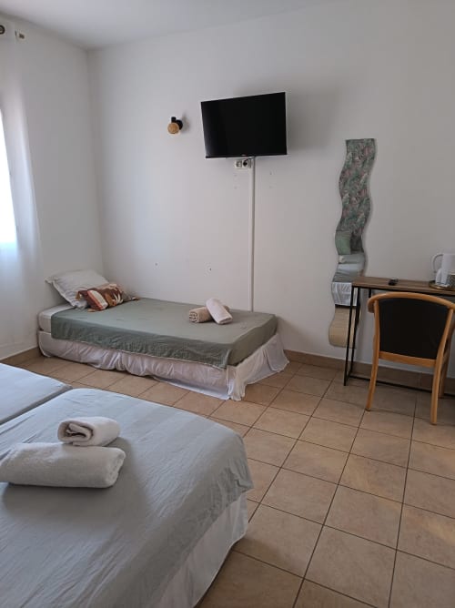 Chambre triple au Clos du Thoronet avec deux lits, télévision murale, bureau et équipements modernes à Le Thoronet