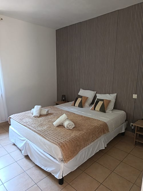 Chambre double au Clos du Thoronet avec lit, serviettes roulées, tête de lit rayée et carrelage