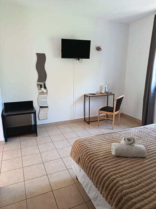 Chambre d'hôtel moderne au Clos du Thoronet avec lit, télévision murale, bureau et carrelage