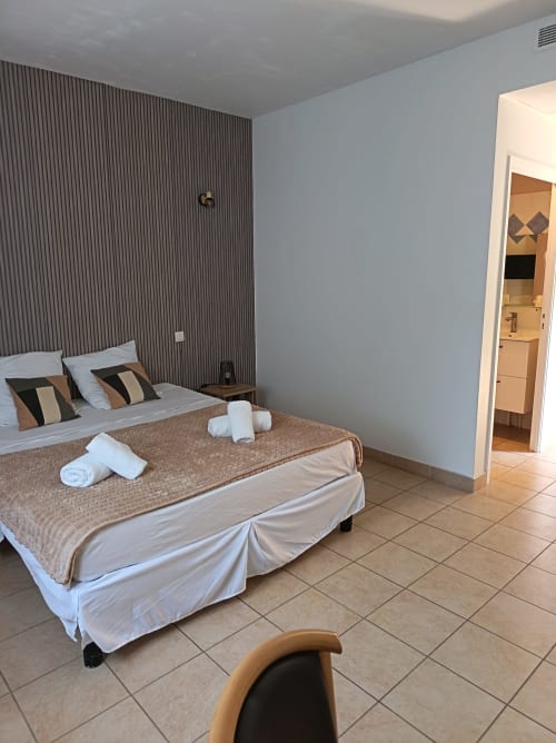 Chambre double au Clos du Thoronet avec mur à rayures, lit blanc, serviettes roulées et salle de bain attenante
