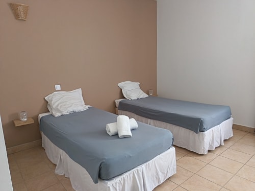 Chambre twin de l'hôtel Le Clos du Thoronet au Thoronet avec deux lits aux draps gris et oreillers blancs