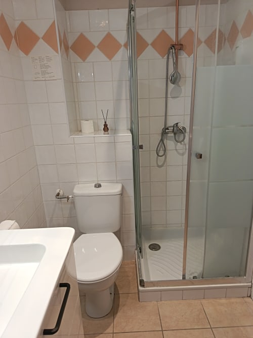 Salle de bain moderne au Clos du Thoronet avec carrelage blanc, douche à l'italienne, toilettes et motif géométrique orange décoratif