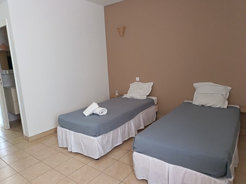 Chambre twin de l'hôtel Le Clos du Thoronet au Thoronet avec deux lits, murs beige et carrelage.