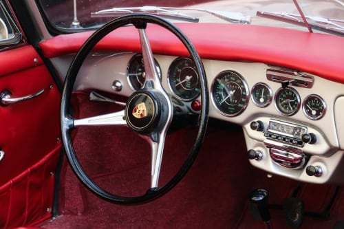 Classic red Porsche dashboard with vintage steering wheel and gauges at Agriturismo La Frattina, Siena