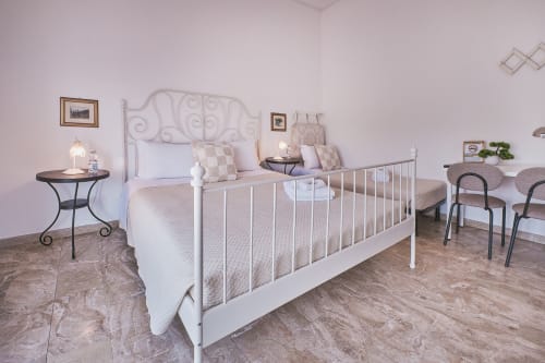 Luminosa camera tripla a Casa Mia B&B con letto in metallo bianco, testata tradizionale, arredamento neutro, pavimento in legno e comodino