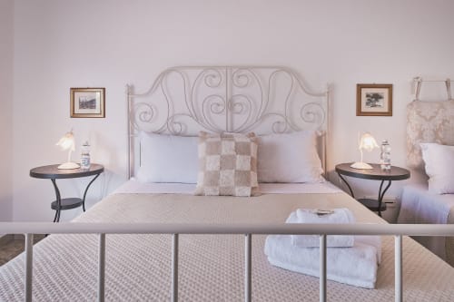 Elegante camera tripla a Casa Mia B&B con testata ornamentale, letti gemelli, comodini e pareti rosa chiaro