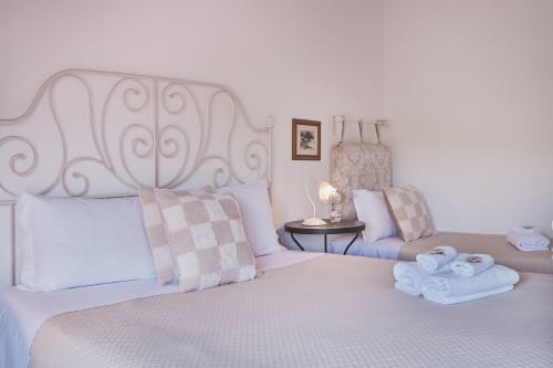 Elegante camera da letto di Casa Mia B&B con testata in ferro battuto ornato, cuscini a quadri e asciugamani bianchi sul letto