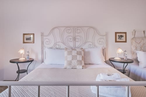 Elegante camera tripla a Casa Mia B&B in Italia con testata in ferro battuto ornato, biancheria bianca e comodini gemelli
