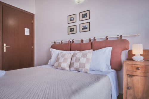 Camera moderna di Casa Mia B&B con testata in terracotta, biancheria bianca, comodino in legno e opera d'arte incorniciata
